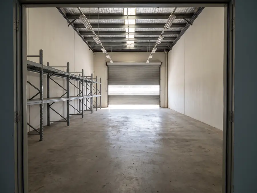 Leergeräumte Lagerhalle mit leerem Regal und offenem Rolltor, bereit zur Übergabe.