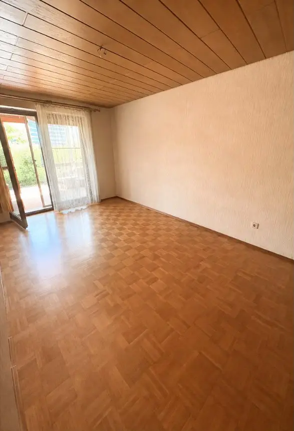 Dasselbe Wohnzimmer nach der Entrümpelung: vollständig leergeräumt, Parkettboden besenrein.